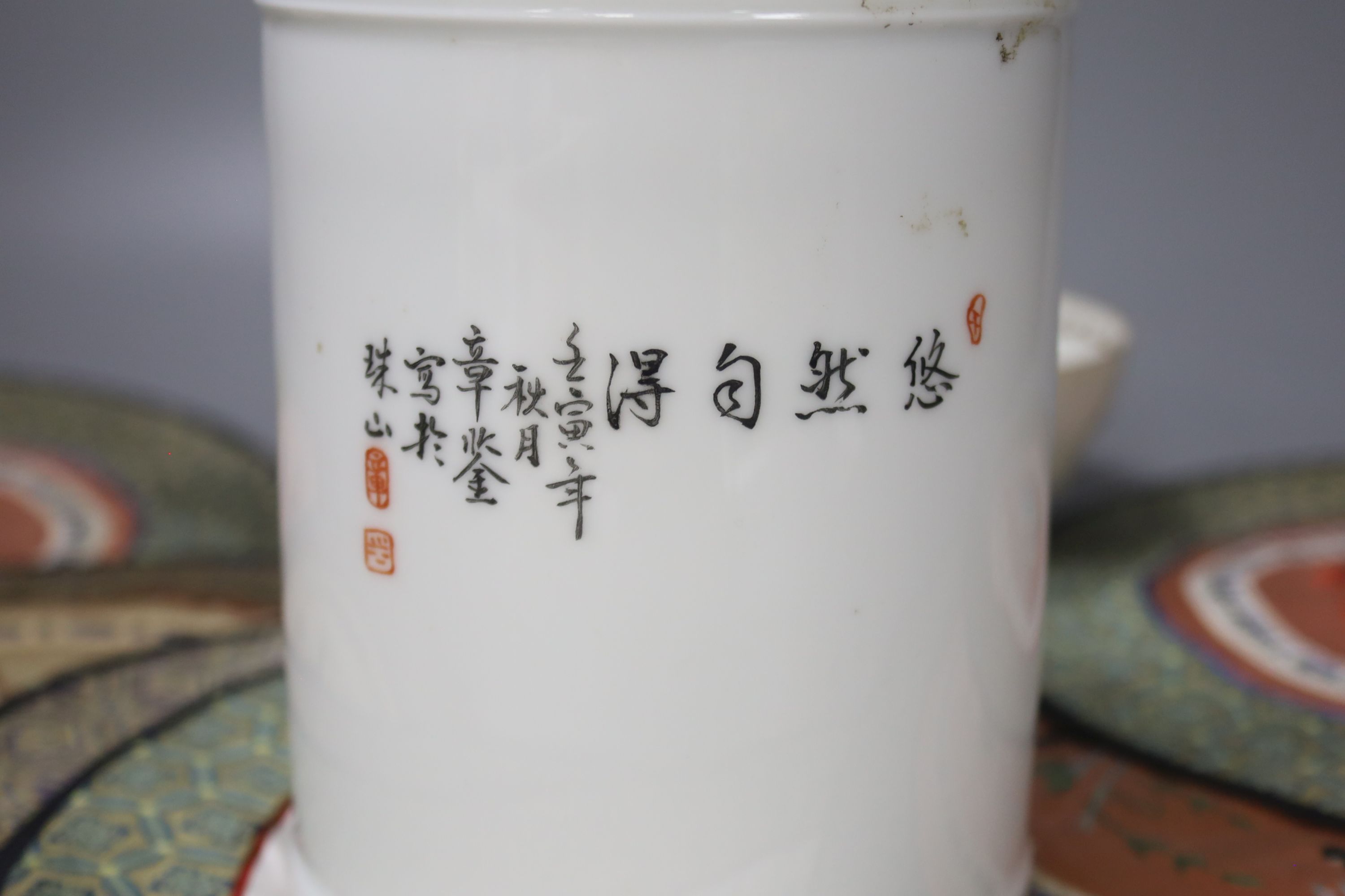 A Chinese porcelain brush pot, various embroidered silk mats etc.